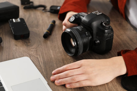 Professional photographer with laptop, camera and other equipment at wooden table, closeupの写真素材