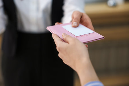 Receptionist giving passport and hotel key card to guest indoors, closeupの写真素材