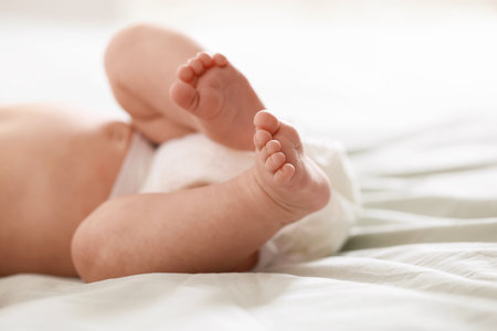 Cute newborn baby in diaper lying on bed indoors, closeup. Space for textの写真素材