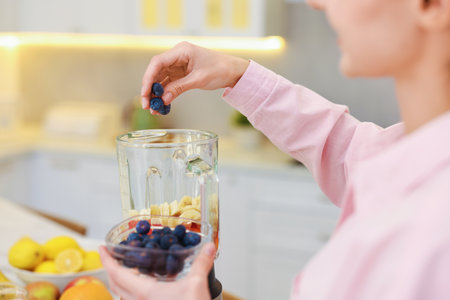 Woman making delicious smoothie with blender indoors, closeupの写真素材