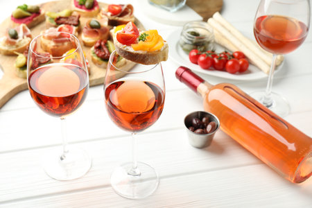 Tasty bruschettas with prosciutto and rose wine served on white wooden table, closeupの写真素材