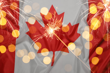 Flag of Canada, burning sparkler, fireworks and bokeh lights. National holidayの写真素材