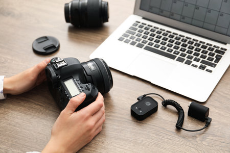 Professional photographer with laptop, camera and other equipment at wooden table, closeupの写真素材