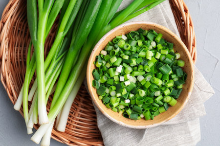 Whole and cut fresh green onions on gray table, top viewの写真素材
