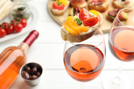 Tasty bruschettas with prosciutto and rose wine served on white wooden table, closeupの写真素材