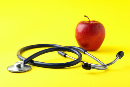 Ripe apple and stethoscope on yellow background, selective focus. Space for textの写真素材