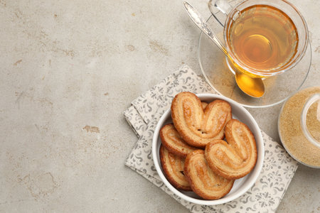 Yummy palmiers, tea and brown sugar on light gray table, flat lay. Space for textの写真素材