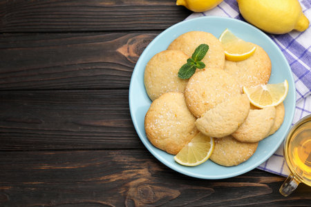 Tasty lemon cookies and fruit slices on black wooden table, flat lay. Space for textの写真素材