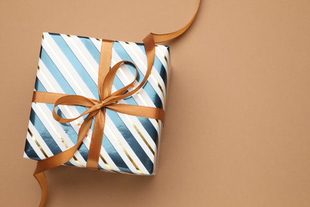 Beautiful wrapped gift on brown background, top view. Space for textの写真素材