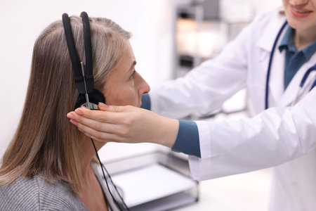 Hearing test. Doctor adjusting patient's audiometric headphones in clinic, closeupの写真素材