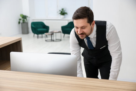 Receptionist working at reception desk in hotelの写真素材