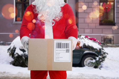 Santa Claus holding parcel near car on snowy street, closeupの写真素材