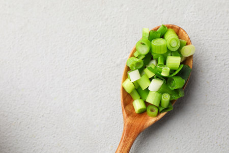 Cut green onion in wooden spoon on gray table, top view. Space for textの写真素材