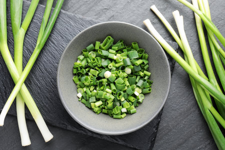 Whole and cut fresh green onions on black table, flat layの写真素材