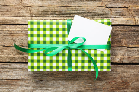 Beautiful gift box with blank card on wooden table, top view