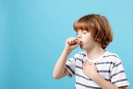 Little boy coughing on light blue background, space for text. Cold symptomの写真素材