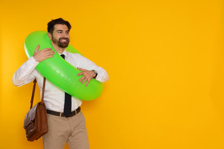 Businessman with inflatable ring and briefcase on orange background, space for textの写真素材
