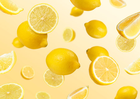 Fresh lemons falling on orange gradient background. Citrus fruitの写真素材