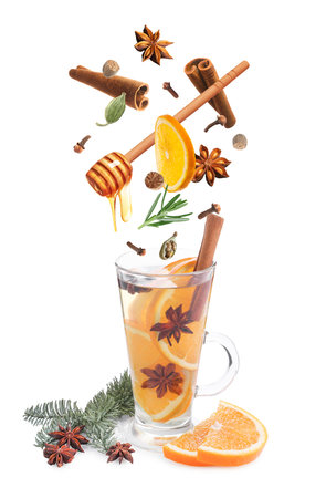 Mulled wine recipe. Spices and other ingredients falling into glass cup with beverage against white backgroundの写真素材