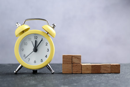 Alarm clock and blank wooden cubes on black tableの写真素材