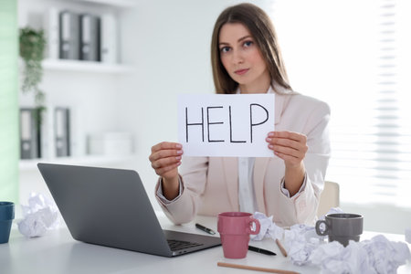 Woman with laptop and sign Help at table in office, selective focus