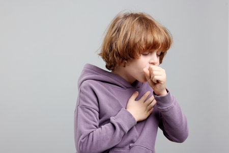 Little boy coughing on light background. Cold symptomの写真素材