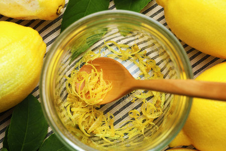 Jar with lemon zest, spoon and fresh fruits on tablecloth, flat lay