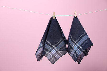 Stylish handkerchiefs hanging from string against pink background