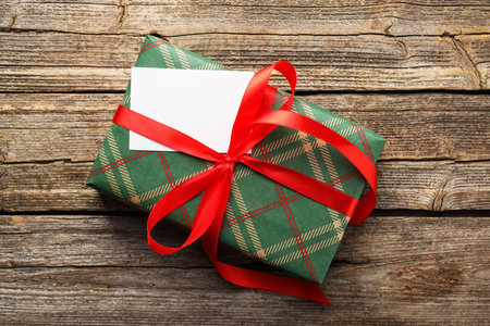Beautiful gift box with blank card on wooden table, top view