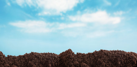 Soil under blue sky with clouds, closeup viewの写真素材