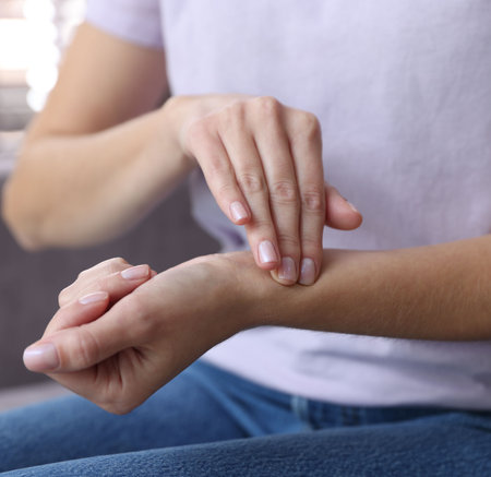 Woman checking her pulse with fingers at home, closeup