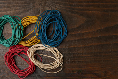 Many colorful rubber bands on wooden table, flat lay. Space for textの写真素材