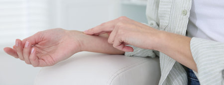 Woman checking her pulse with fingers at home, closeup. Space for text