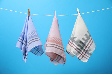 Stylish handkerchiefs hanging from string against light blue backgroundの写真素材
