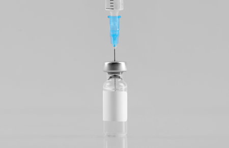 Filling syringe with vaccine from glass vial at mirror surface against gray background, closeupの写真素材