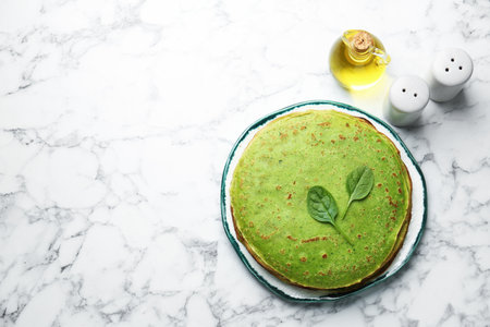 Tasty spinach crepes, leaves and spices on white marble table, flat lay. Space for textの写真素材