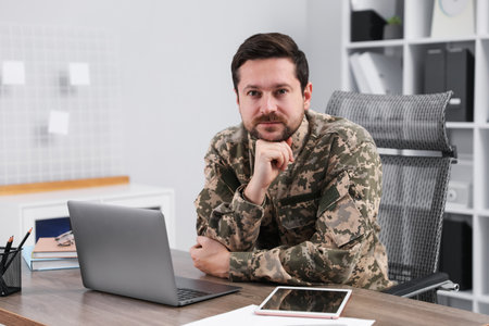 Military education. Student in soldier uniform at wooden desk in officeの写真素材