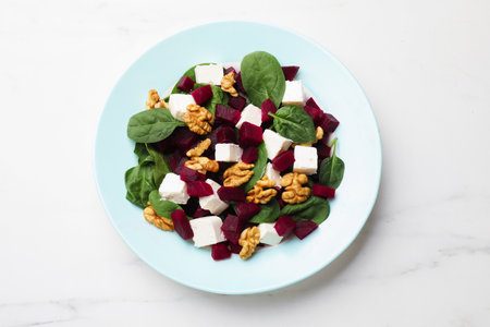 Salad with beetroot, feta cheese, spinach and walnuts on white table, top viewの写真素材