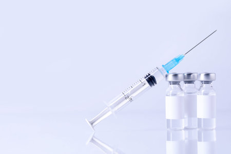 Vaccine in vials and syringe on mirror surface against gray background, closeup. Space for textの写真素材
