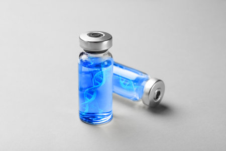 DNA strands in vials with vaccine on gray backgroundの写真素材