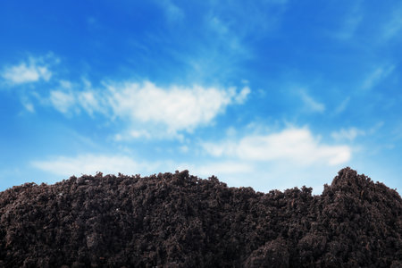Soil under blue sky with clouds, closeup viewの写真素材