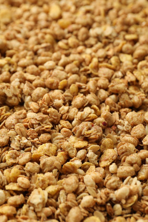 Tasty granola with oat flakes as background, closeup