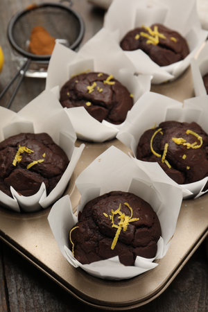 Tasty chocolate muffins with lemon zest on wooden table, closeupの写真素材