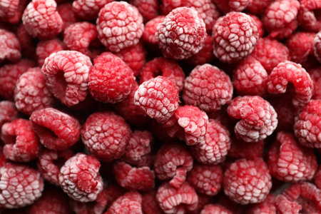 Frozen ripe raspberries as background, top view