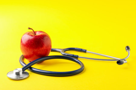 Ripe apple and stethoscope on yellow background, closeup. Space for textの写真素材