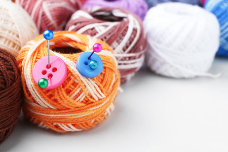Ball of yarns with pins and buttons on white table, closeup. Space for text