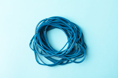 Many rubber bands on light blue background, top view