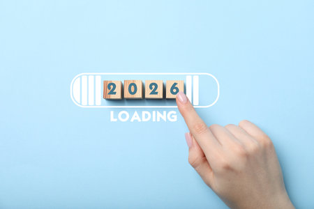 Woman touching wooden cubes with numbers on light blue background, top view