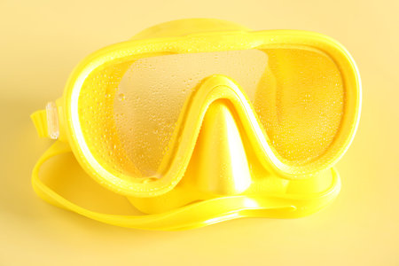 Yellow diving mask with water drops on beige background, closeupの写真素材