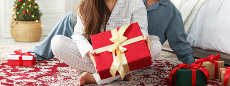 Happy couple in pajamas with Christmas gift at home